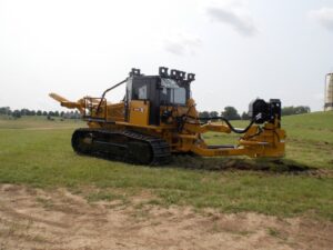 BRON 250 utility tractor on tracks in an open field, equipped for heavy-duty trenching and cable installation.